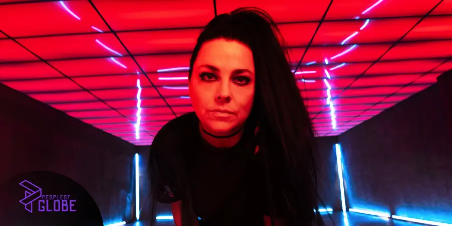 Amy Lee, lead singer of Evanescence, performing live with a piano in a high-fashion black stage outfit.