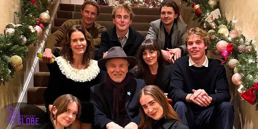 Don Johnson sitting with his children and family members on a decorated staircase during a holiday gathering.