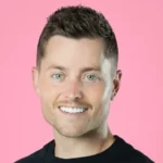 A high-quality professional headshot of Sawyer Hemsley, co-founder of Crumbl Cookies, against a pink background.