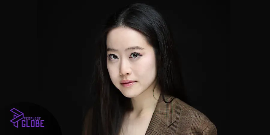 A professional headshot of Stephanie Soo in a brown blazer against a dark background.