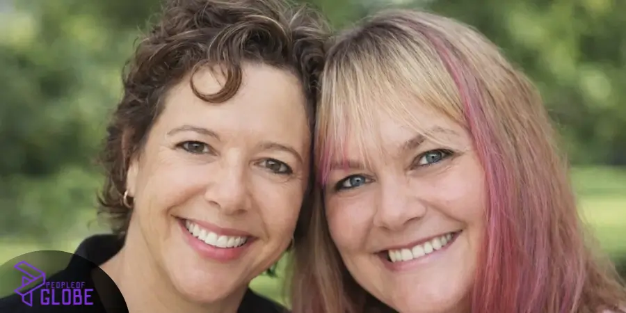 A close-up portrait of two smiling adult women leaning their heads together, showcasing long-term companionship and personal happiness.